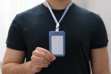 Man with blank badge indoors, closeup view