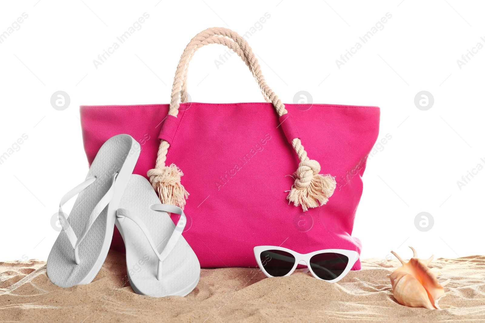 Photo of Stylish coral bag and beach accessories on sand against white background