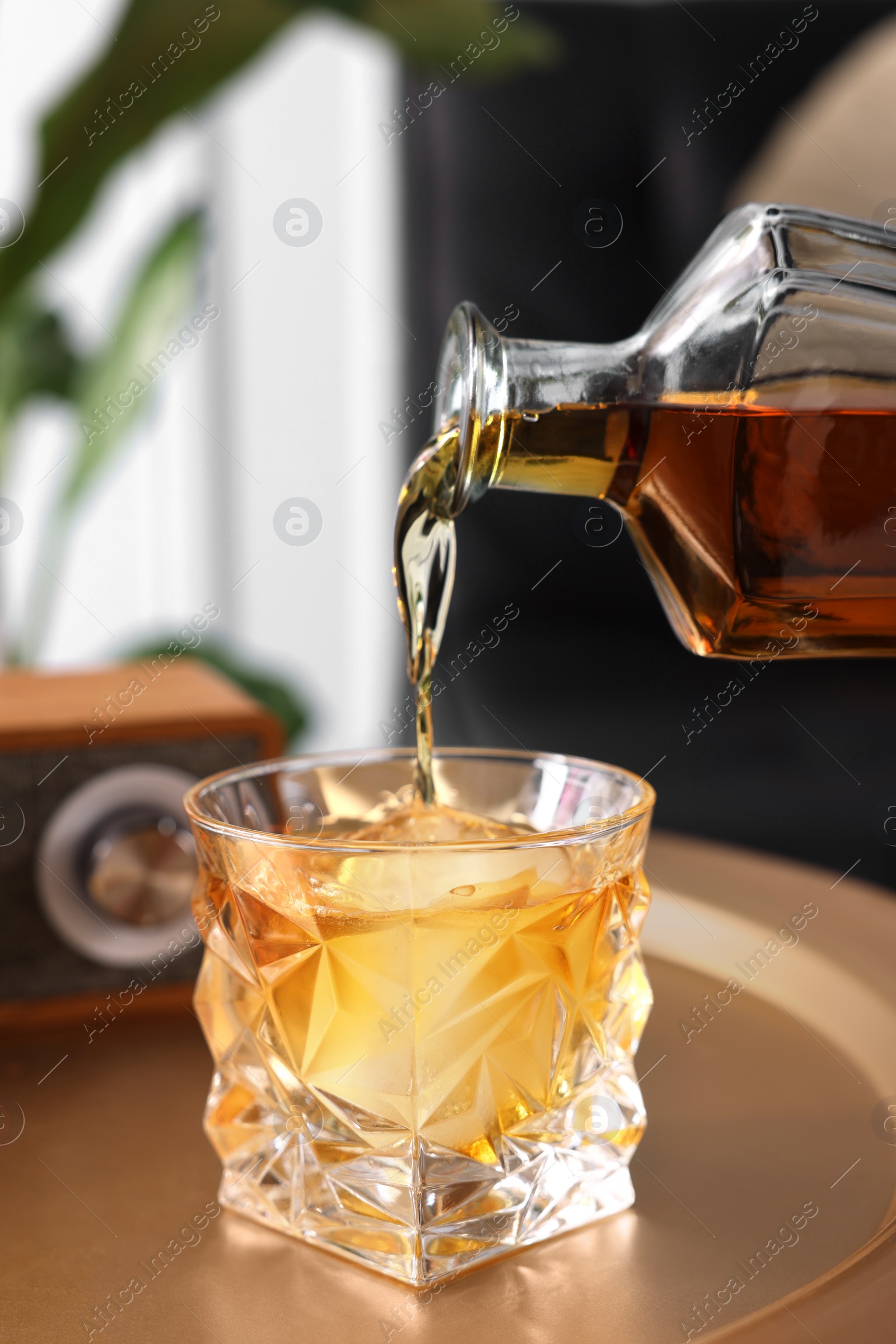 Photo of Pouring alcohol drink into glass in room, closeup. Relax at home