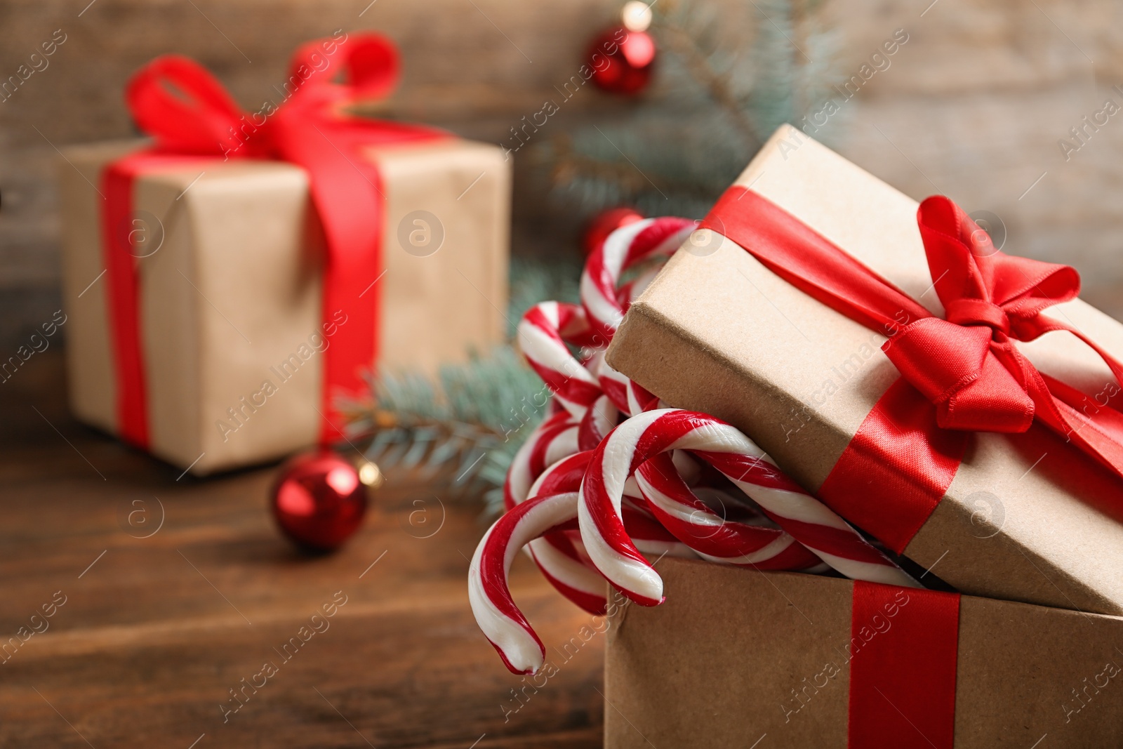 Photo of Candy canes in gift box on wooden table, space for text. Traditional Christmas treat