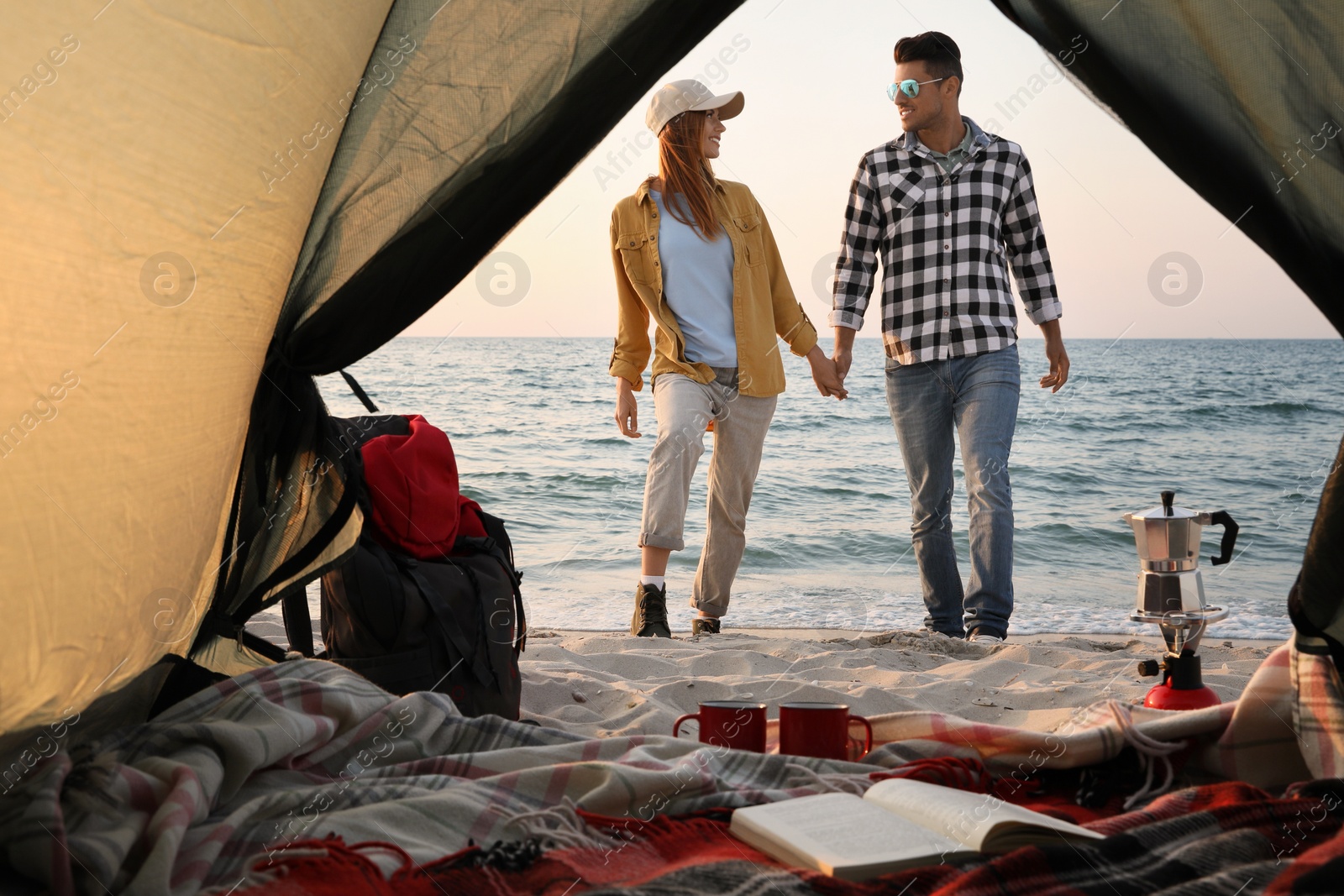 Photo of Couple near sea at sunset, view from camping tent