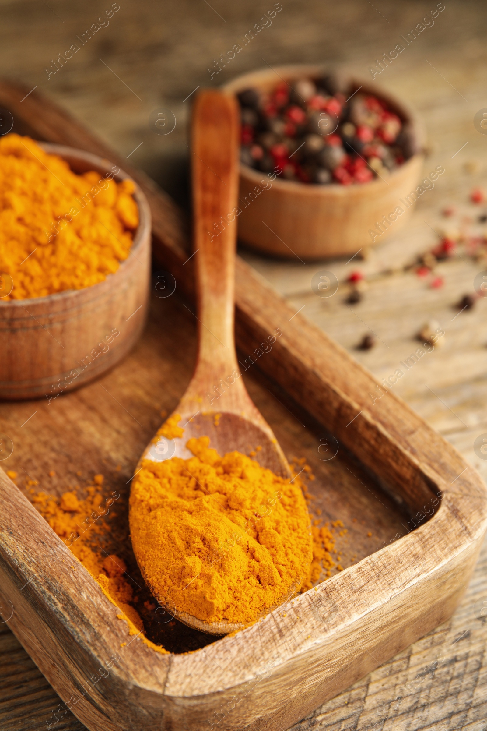 Photo of Spoon and bowl with saffron powder on wooden table