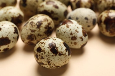 Photo of Many speckled quail eggs on beige background, closeup