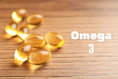 Omega 3. Fish oil capsules on wooden table, closeup