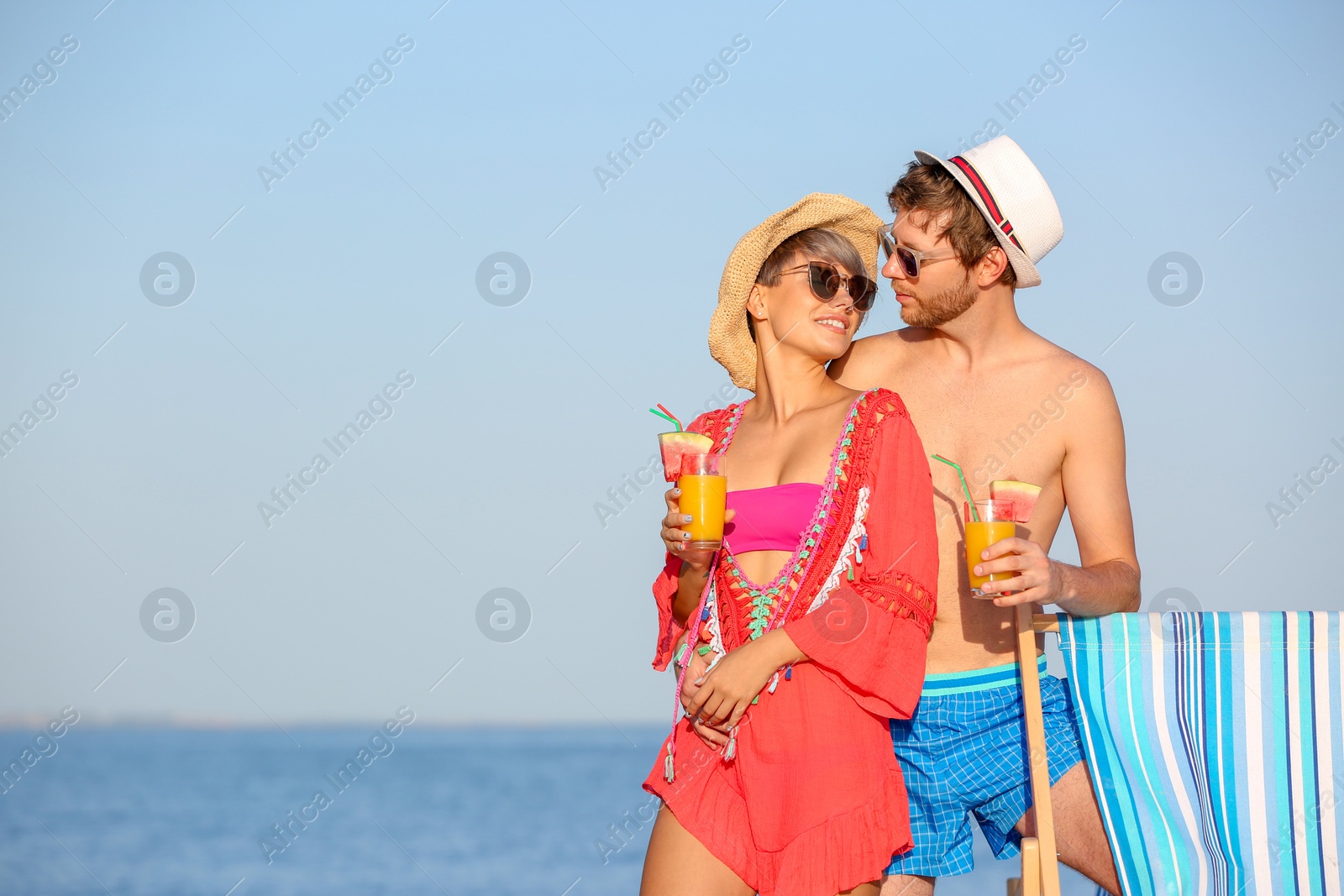 Photo of Young couple with exotic cocktails on beach. Space for text