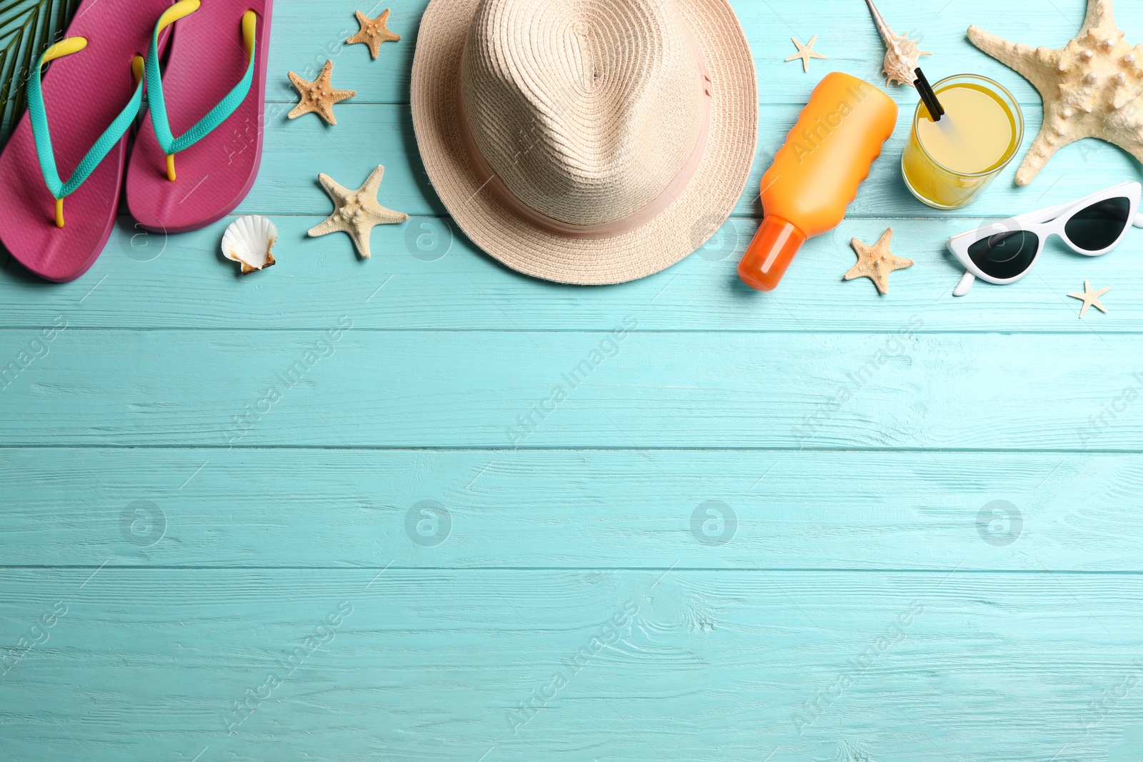 Photo of Beach accessories on light blue wooden background, flat lay. Space for text