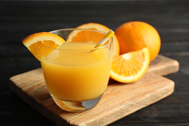 Photo of Glass with orange juice and fresh fruit on wooden board, space for text