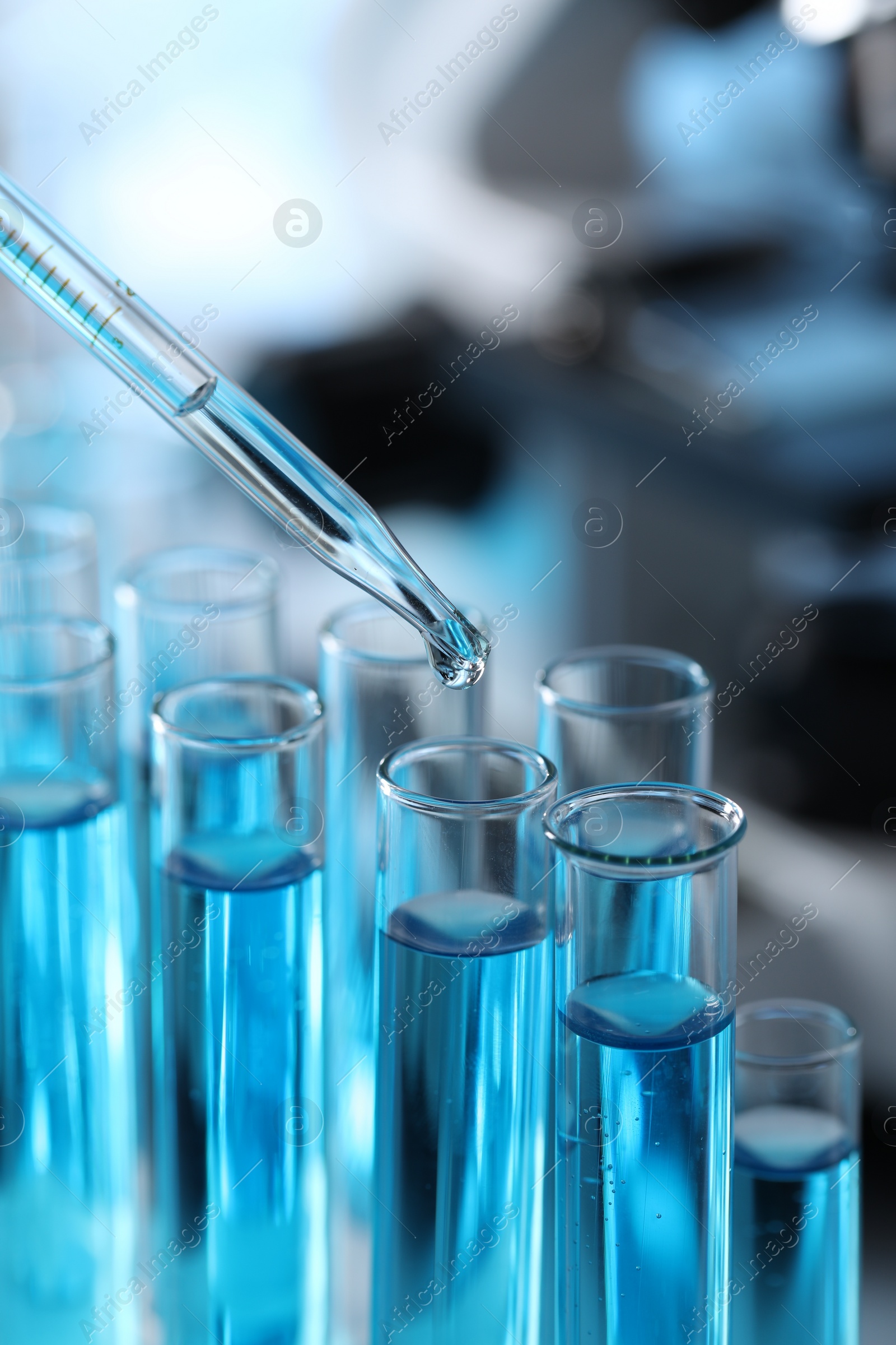 Photo of Dripping liquid from pipette into test tube in laboratory, closeup