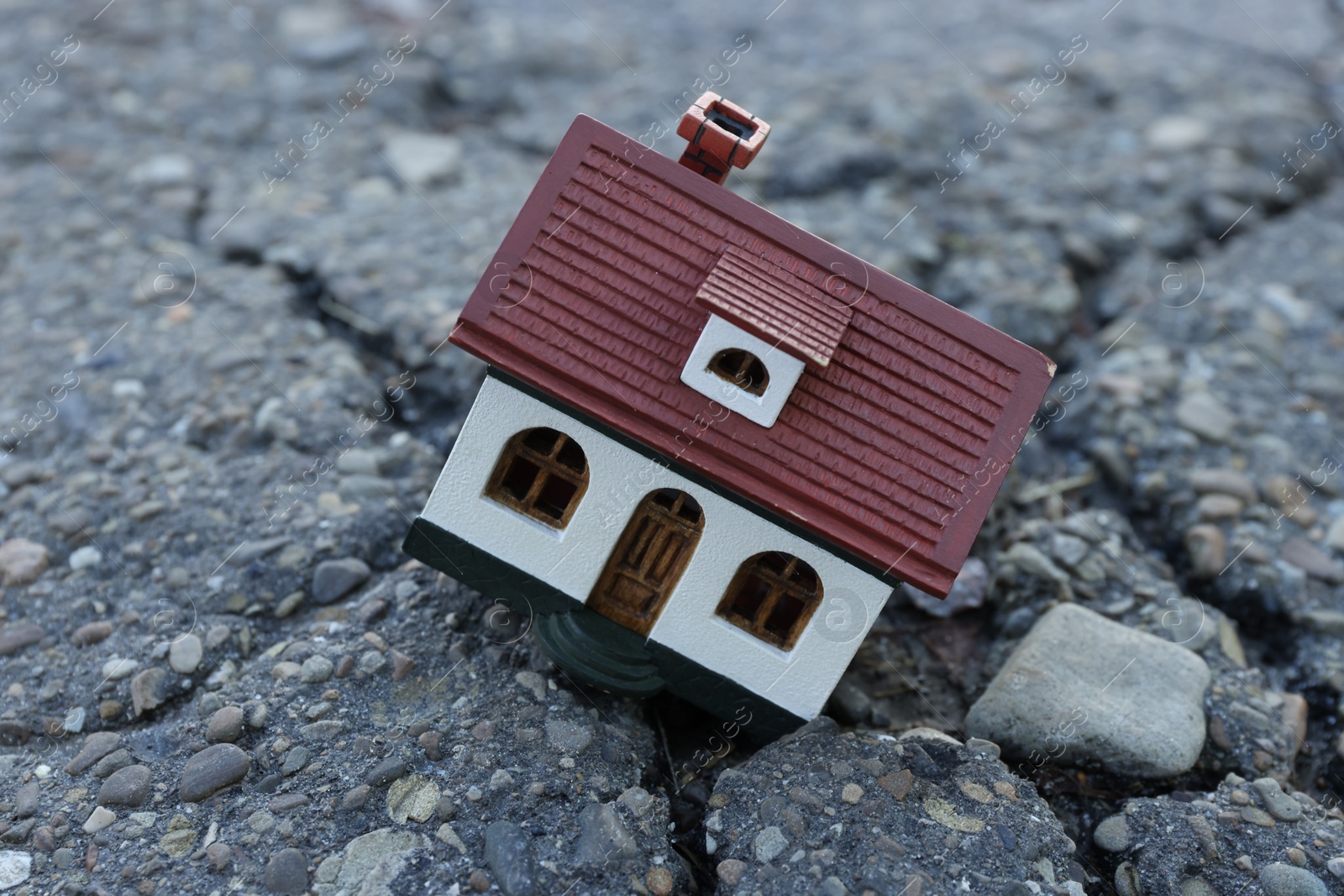 Photo of House model in cracked asphalt. Earthquake disaster