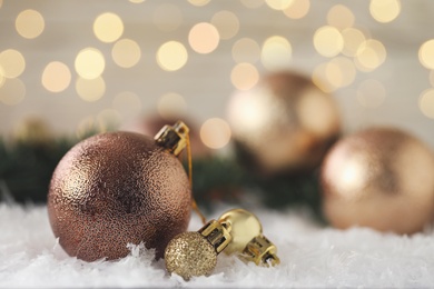 Photo of Beautiful Christmas balls on snow against blurred festive lights. Space for text