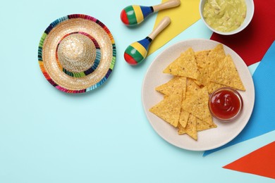 Photo of Flat lay composition with nachos chips and Mexican sombrero hat on light blue background, space for text