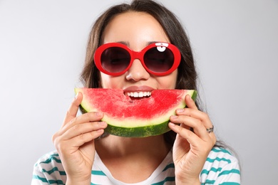 Photo of Beautiful young woman eating watermelon on grey background