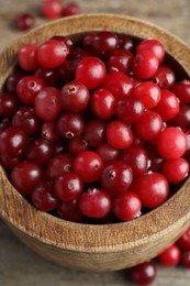 Photo of Cranberries in bowl on wooden table, closeup