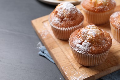 Photo of Delicious sweet muffins on black textured table, closeup. Space for text