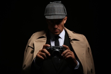 Photo of Old fashioned detective with camera on dark background
