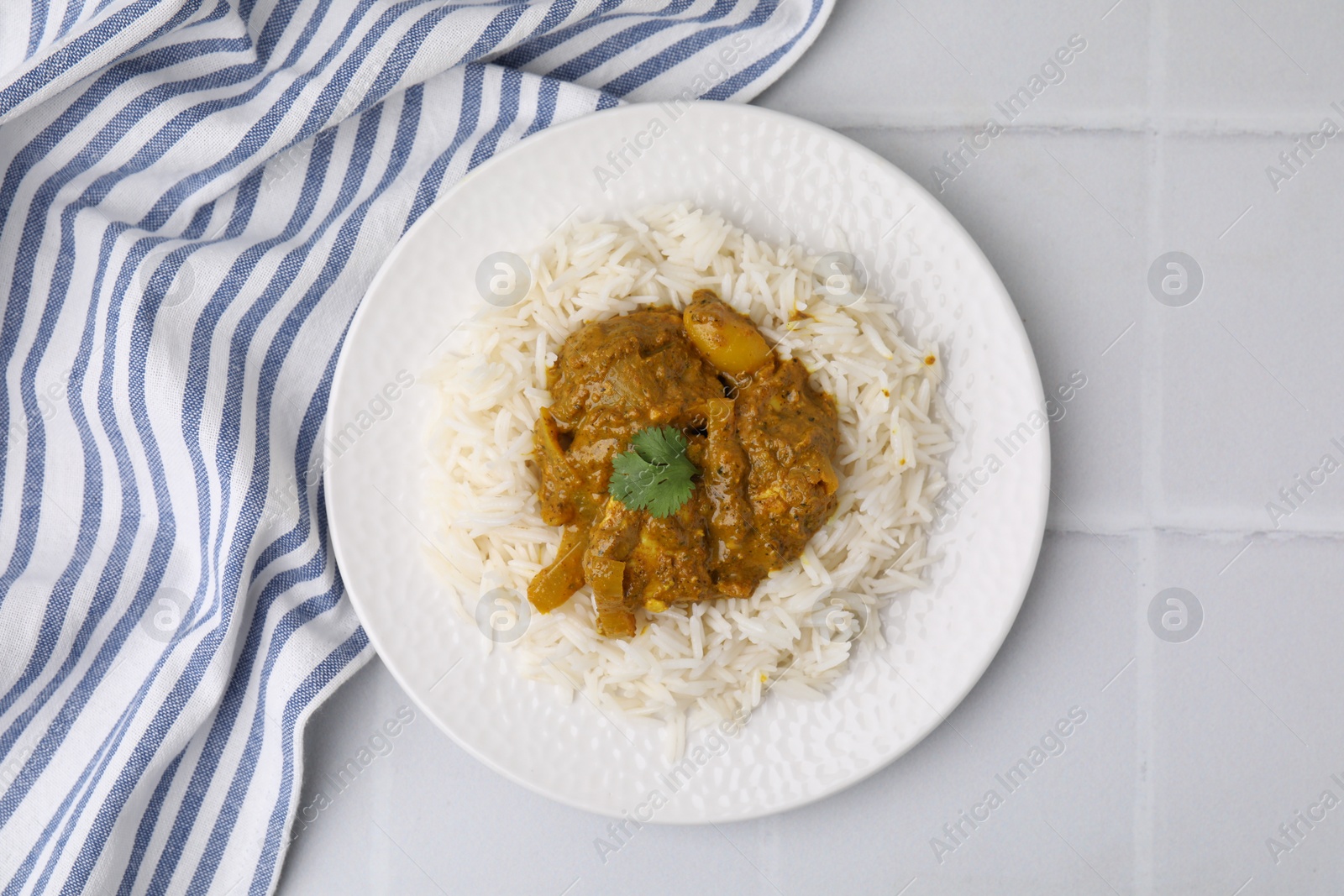 Photo of Delicious chicken curry with rice on white tiled table, top view