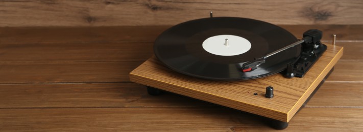 Photo of Turntable with vinyl record on wooden background. Space for text