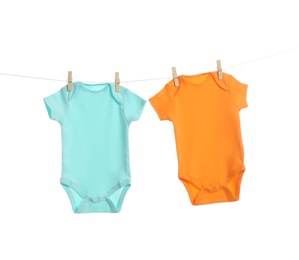 Colorful baby onesies hanging on clothes line against white background. Laundry day