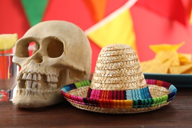 Photo of Mexican sombrero hat and human scull on wooden table