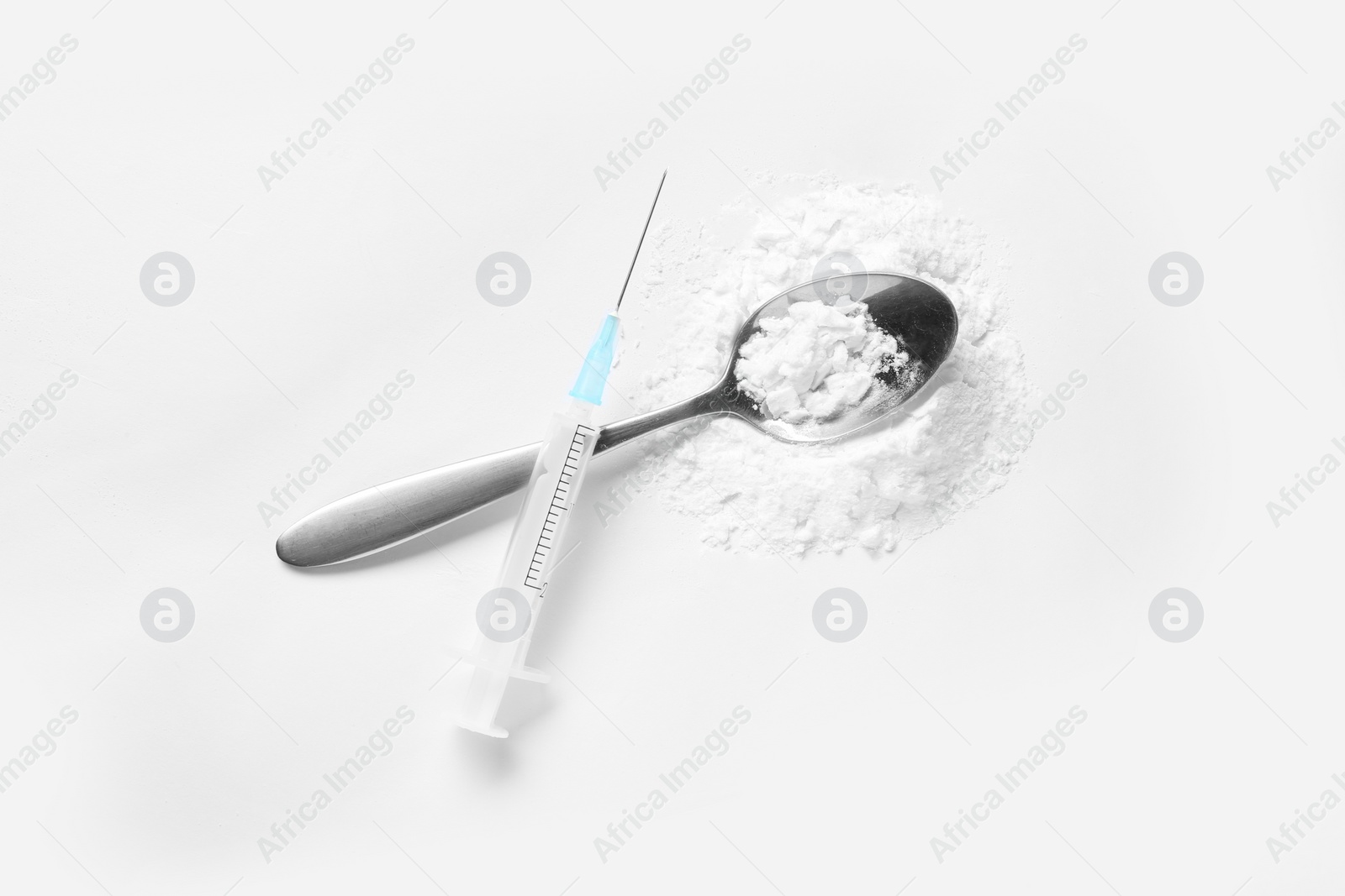 Photo of Spoon with cocaine and empty syringe on white background, top view