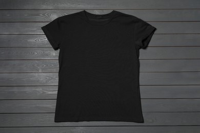 Stylish black T-shirt on gray wooden table, top view