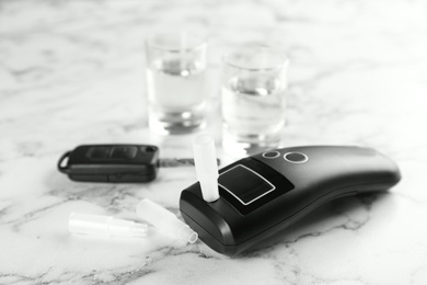 Photo of Modern breathalyzer and mouthpieces on white marble table