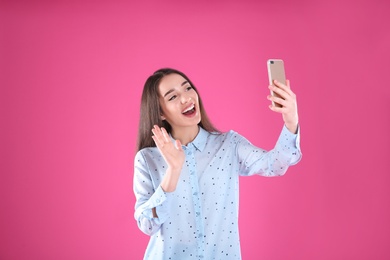 Photo of Woman using mobile phone for video chat on color background