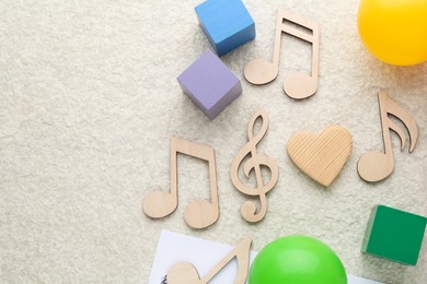 Photo of Wooden notes, music sheet and toys on beige textured background, flat lay with space for text. Baby song concept