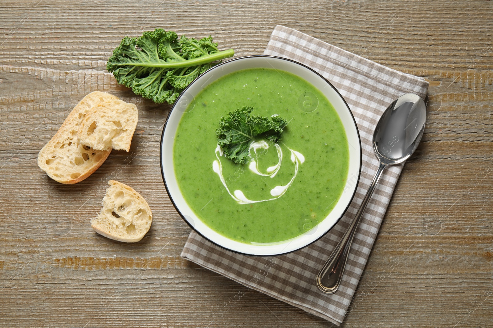 Photo of Tasty kale soup served on wooden table, flat lay