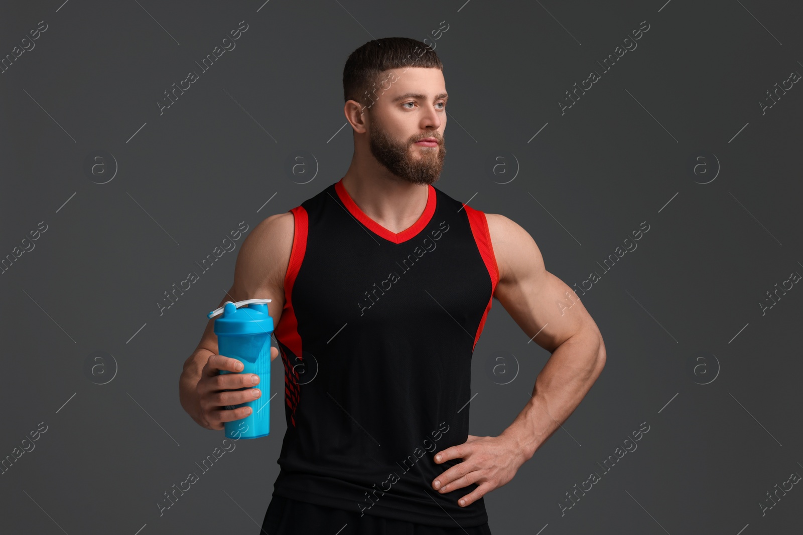 Photo of Young man with muscular body holding shaker of protein on grey background