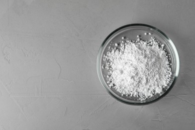 Photo of Petri dish with calcium carbonate powder on grey table, top view. Space for text