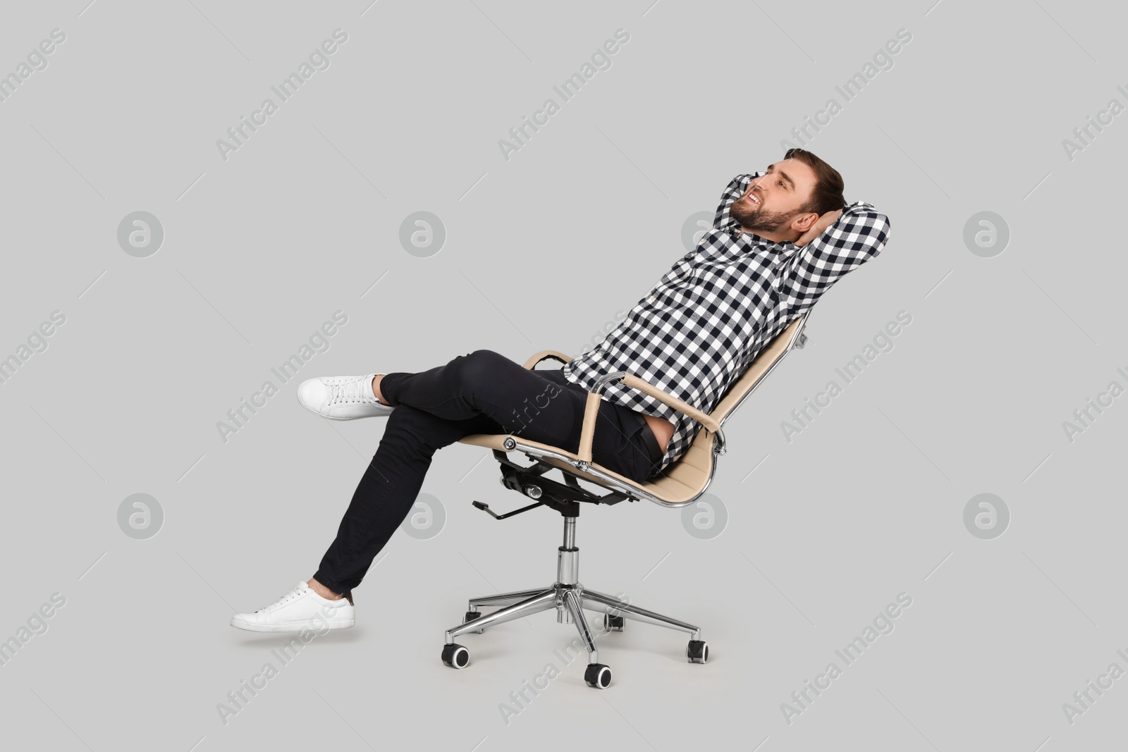 Photo of Young man relaxing in comfortable office chair on grey background