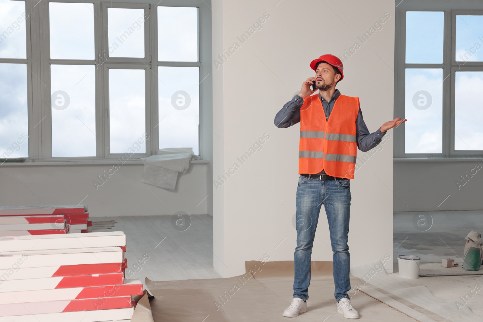Photo of Male industrial engineer in uniform talking on phone indoors