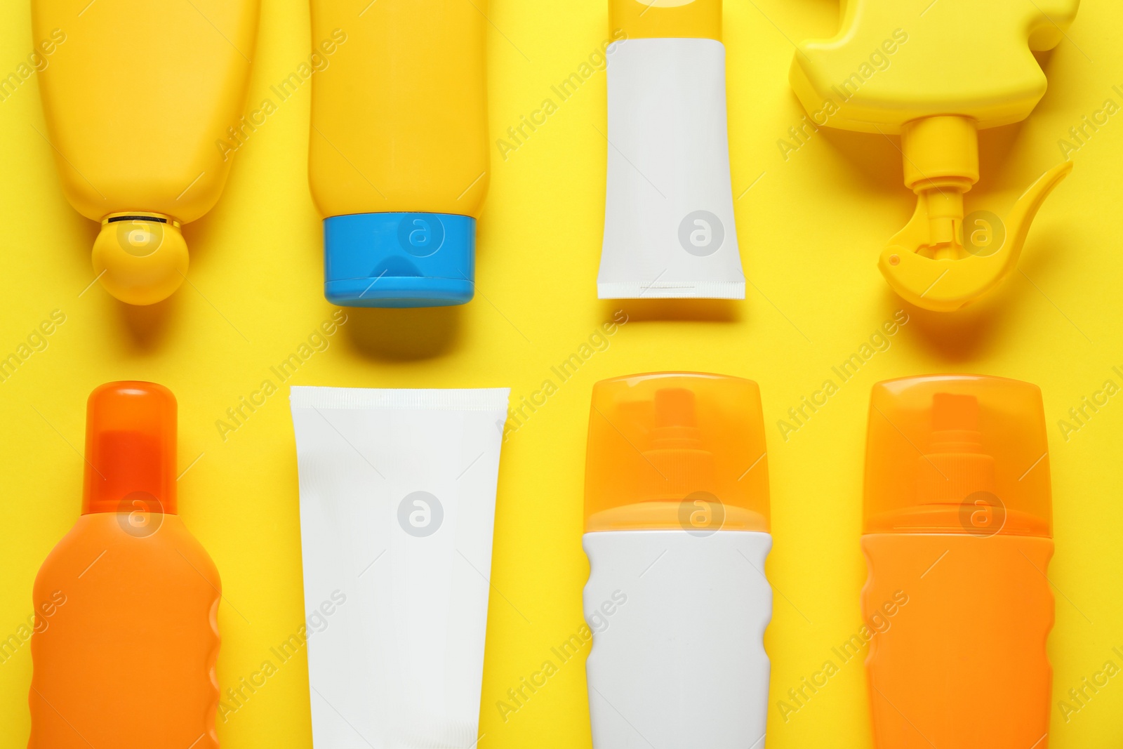 Photo of Suntan products on yellow background, flat lay