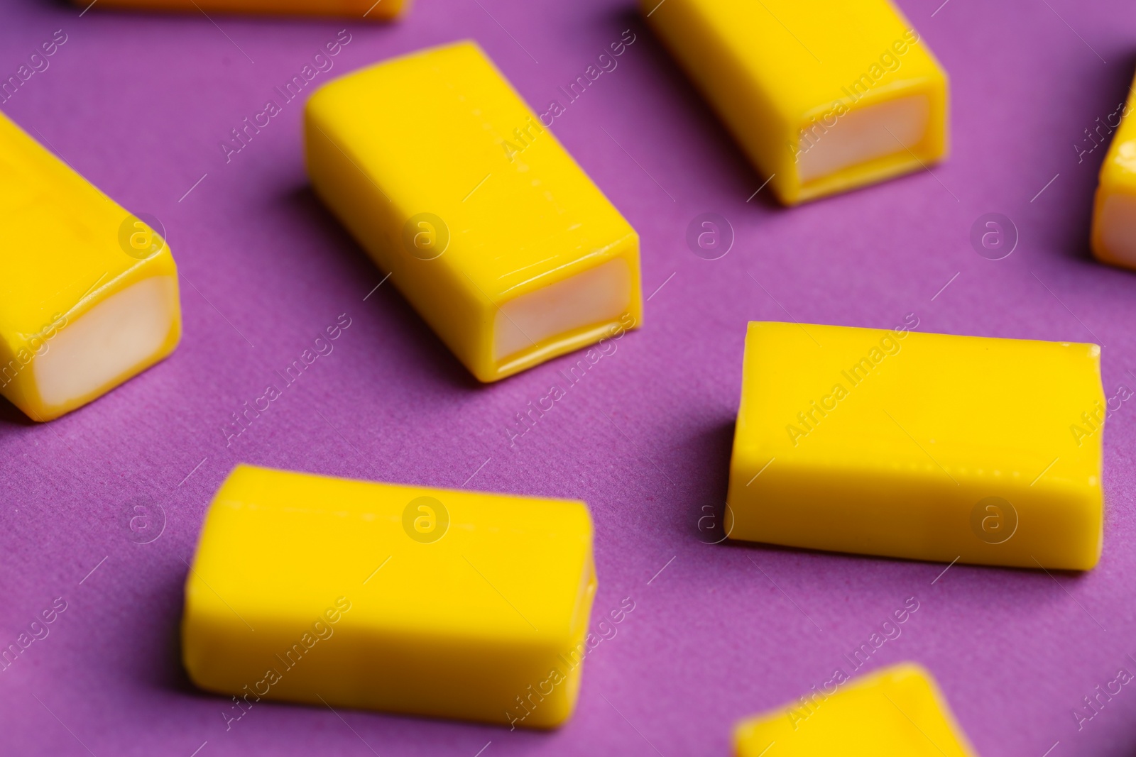 Photo of Tasty yellow bubble gums on purple background, closeup