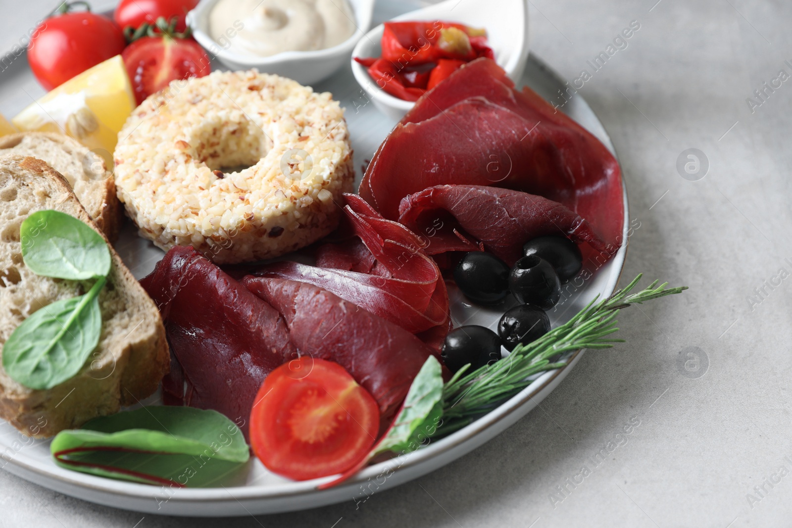 Photo of Delicious bresaola and other ingredients for sandwich on light grey table, closeup