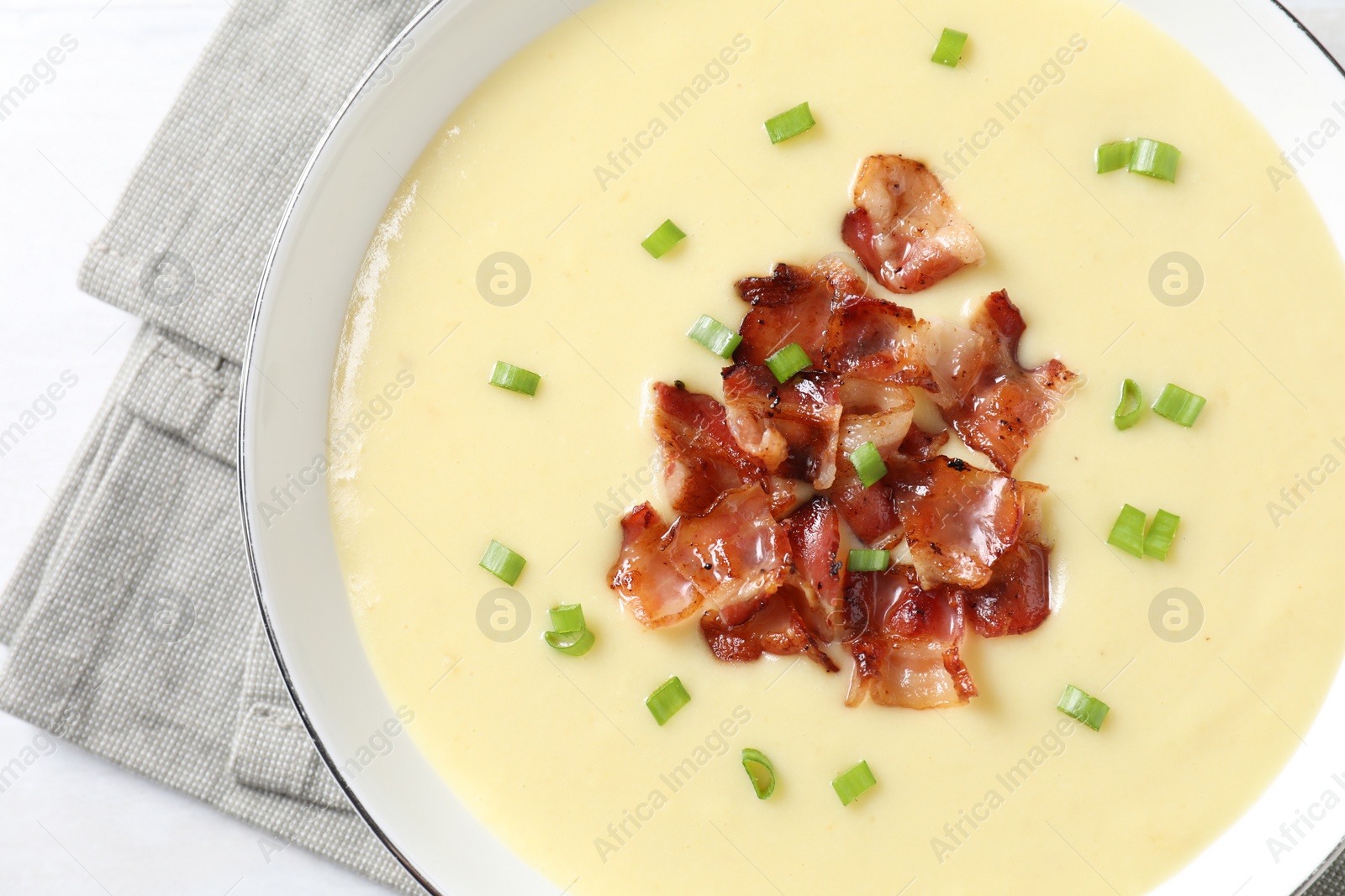 Photo of Tasty potato soup with bacon and green onion in bowl on white table, top view