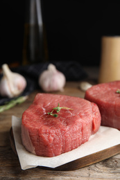 Fresh raw beef cut with thyme on wooden table, closeup