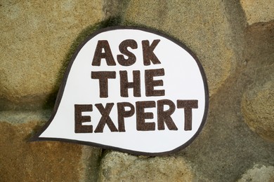Photo of Paper message bubble with phrase Ask The Expert on ground, top view