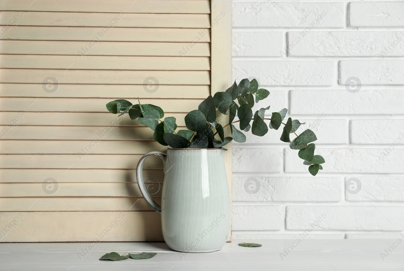 Photo of Beautiful eucalyptus branches in vase on white wooden table