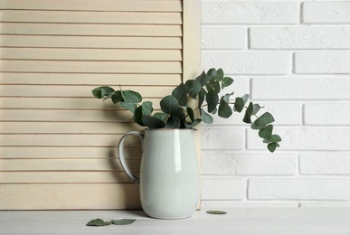 Beautiful eucalyptus branches in vase on white wooden table