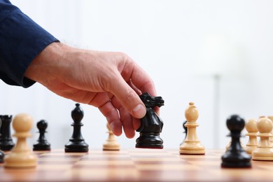 Photo of Man moving knight on chessboard against white background, closeup