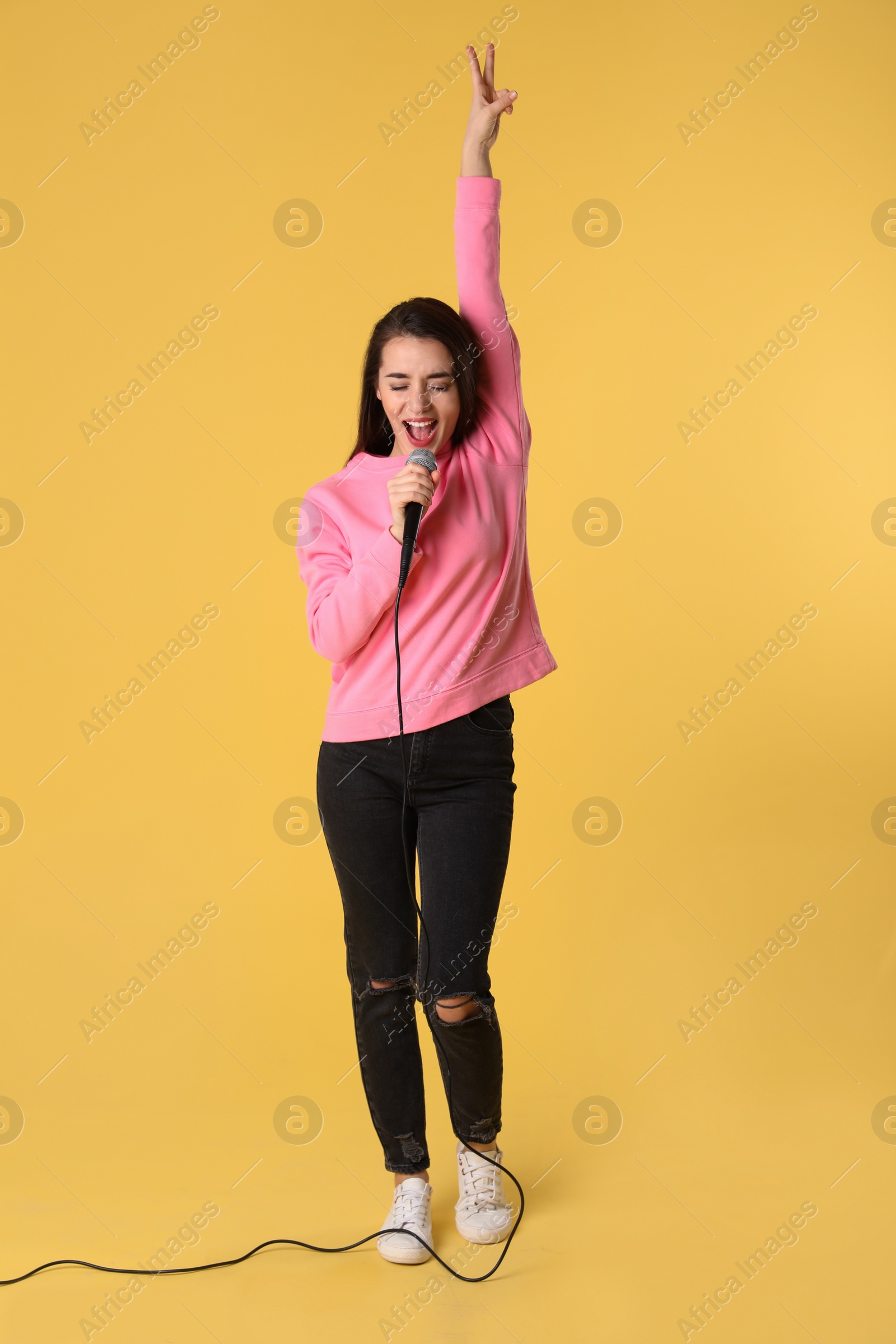 Photo of Young woman wearing casual clothes singing in microphone on color background