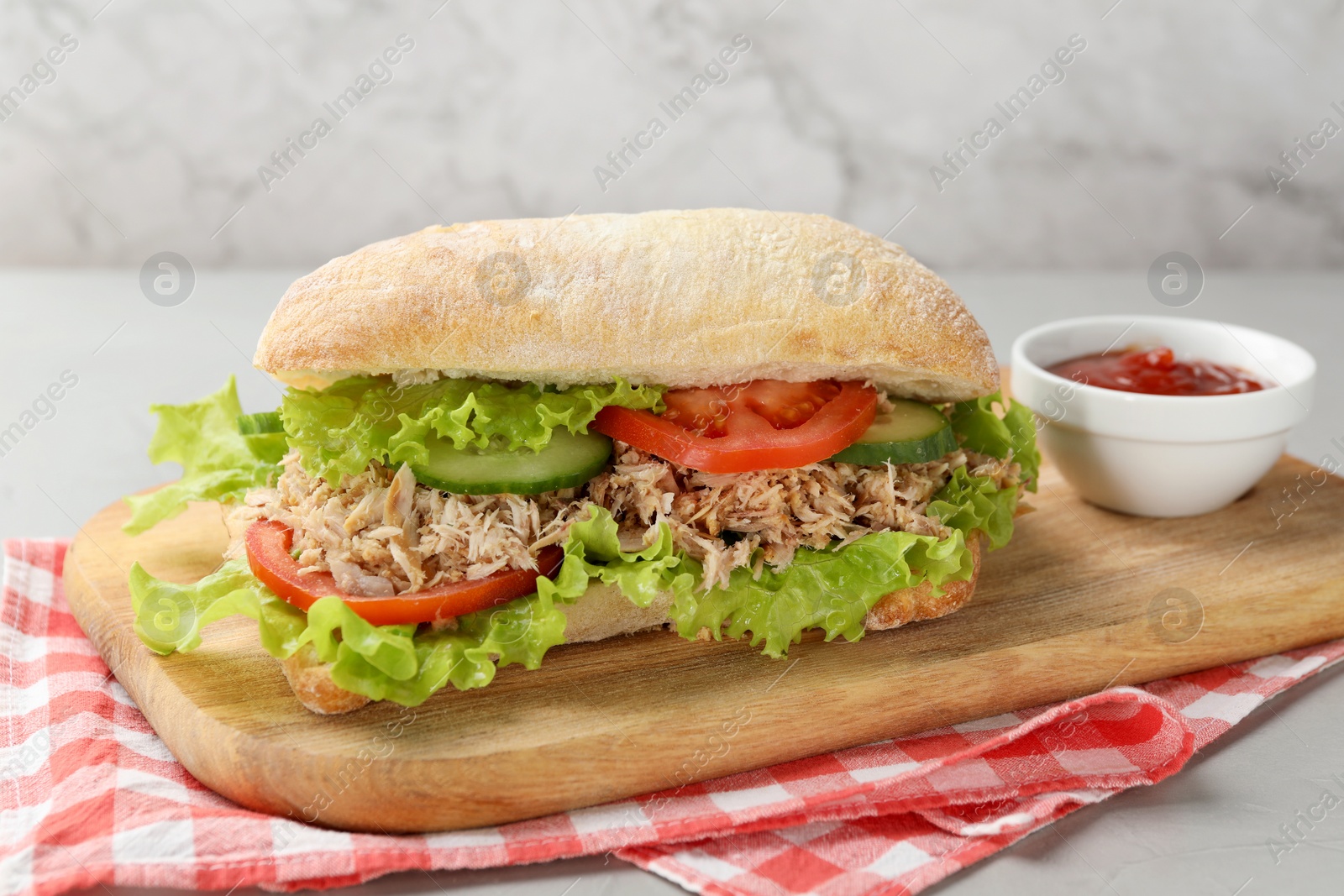 Photo of Delicious sandwich with tuna, vegetables and tomato sauce on light grey table, closeup