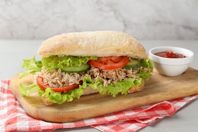 Delicious sandwich with tuna, vegetables and tomato sauce on light grey table, closeup