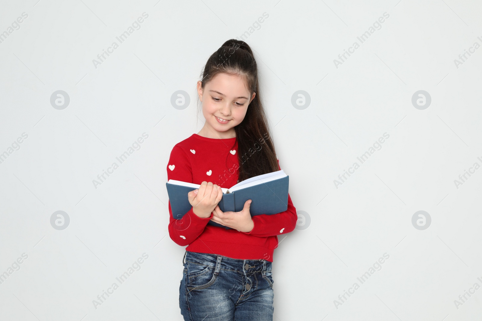 Photo of Cute little girl reading book on white background