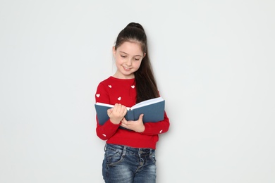 Photo of Cute little girl reading book on white background