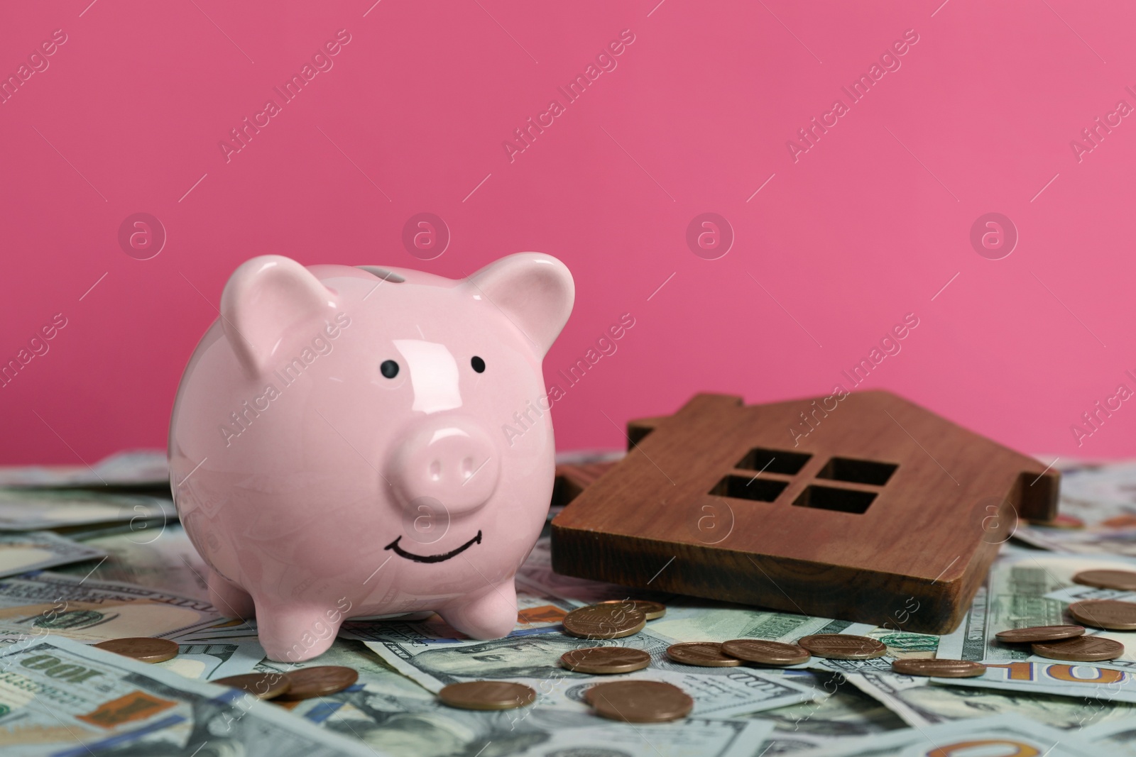 Photo of Piggy bank, house model and money against pink background