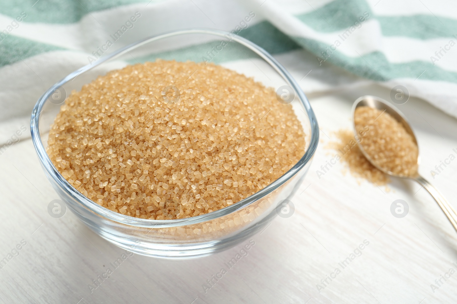 Photo of Brown sugar in glass bowl on white wooden table, closeup