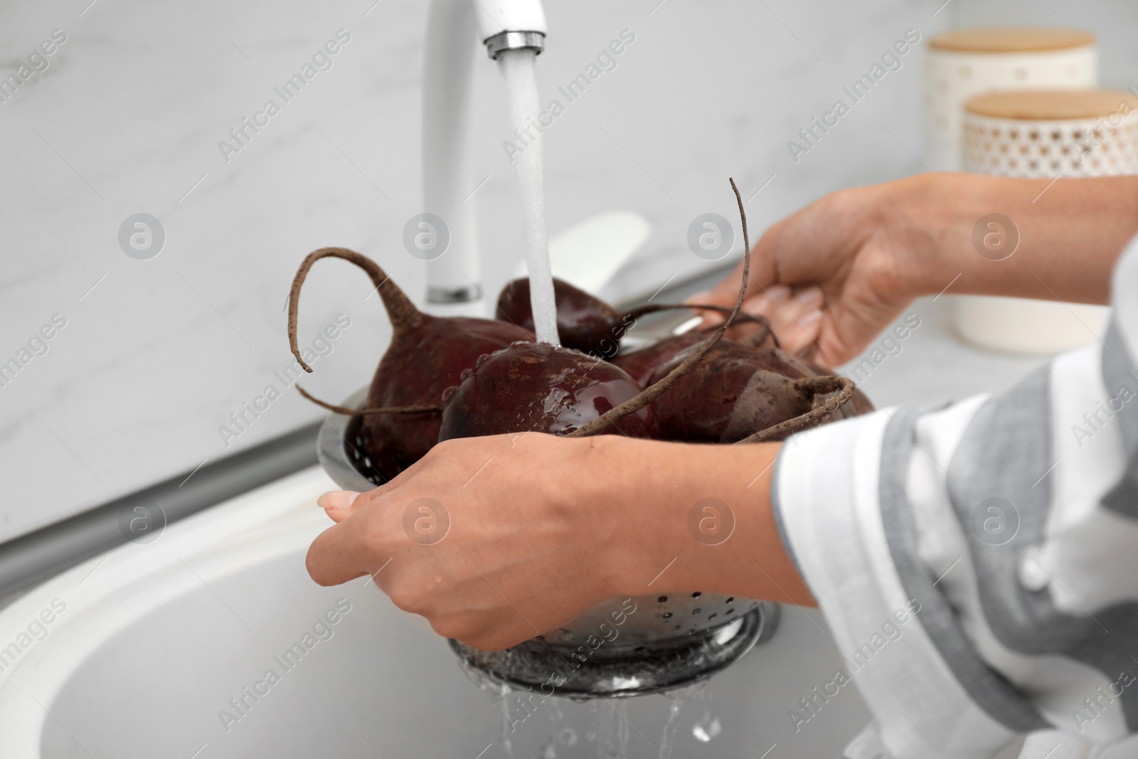 Photo of Woman washing ripe beets in kitchen sink, closeup